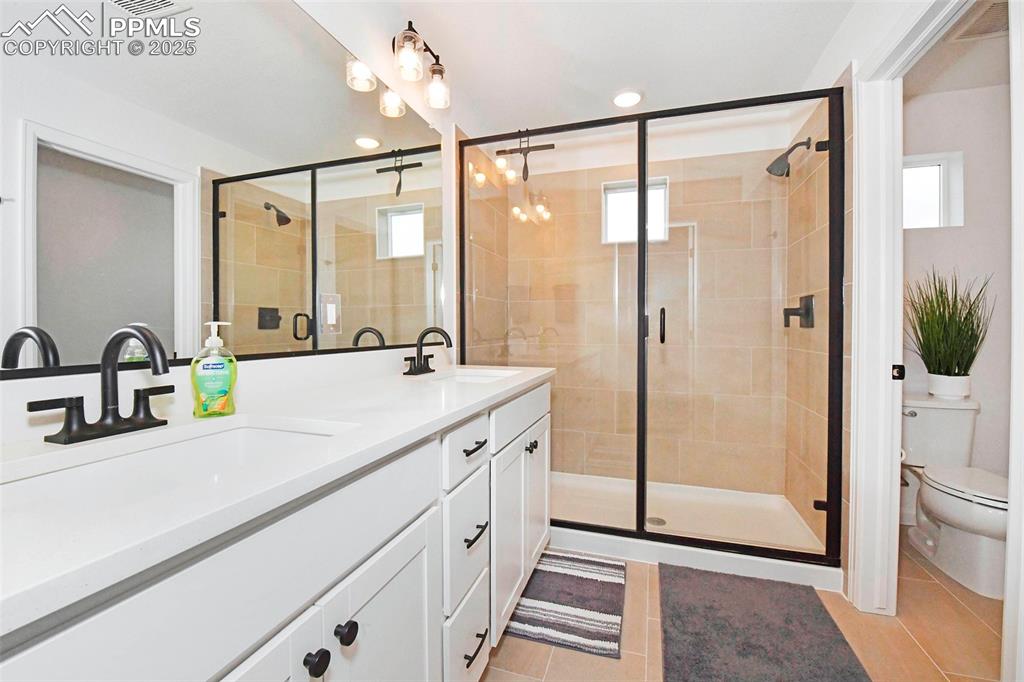 Bathroom with double vanity, light tile patterned floors, a stall shower, and recessed lighting
