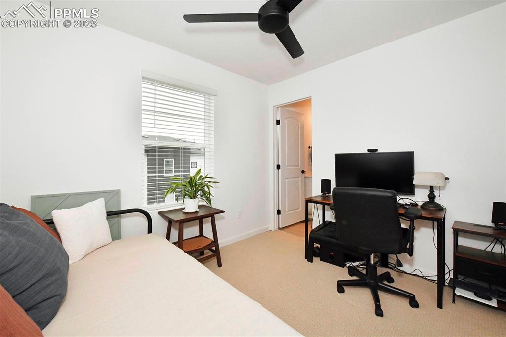 Bedroom with an office area, light colored carpet, and ceiling fan