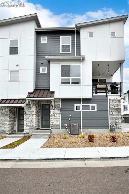 Contemporary house featuring stone siding, a standing seam roof, and a metal roof