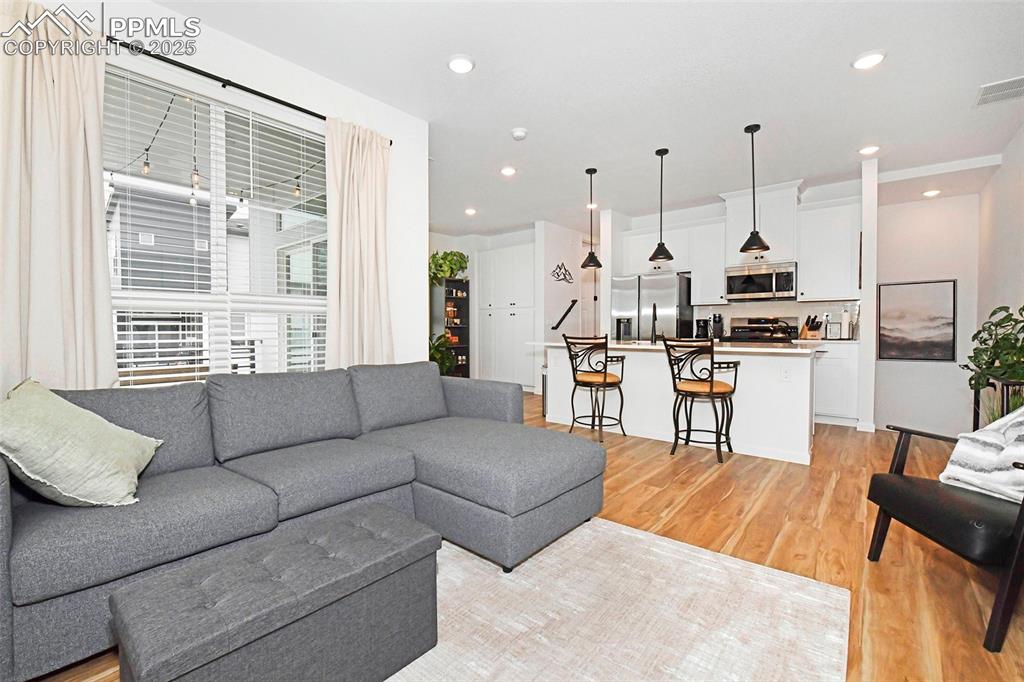 Living area with light wood finished floors and recessed lighting