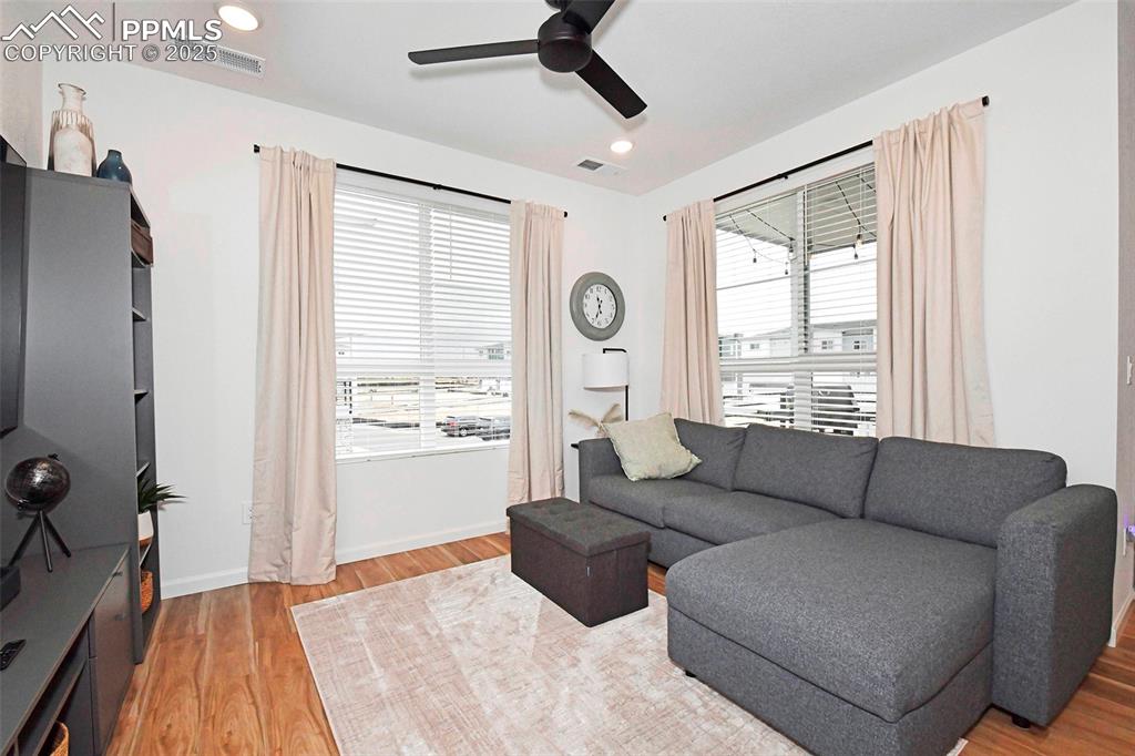 Living area with light wood-style flooring, ceiling fan, and recessed lighting