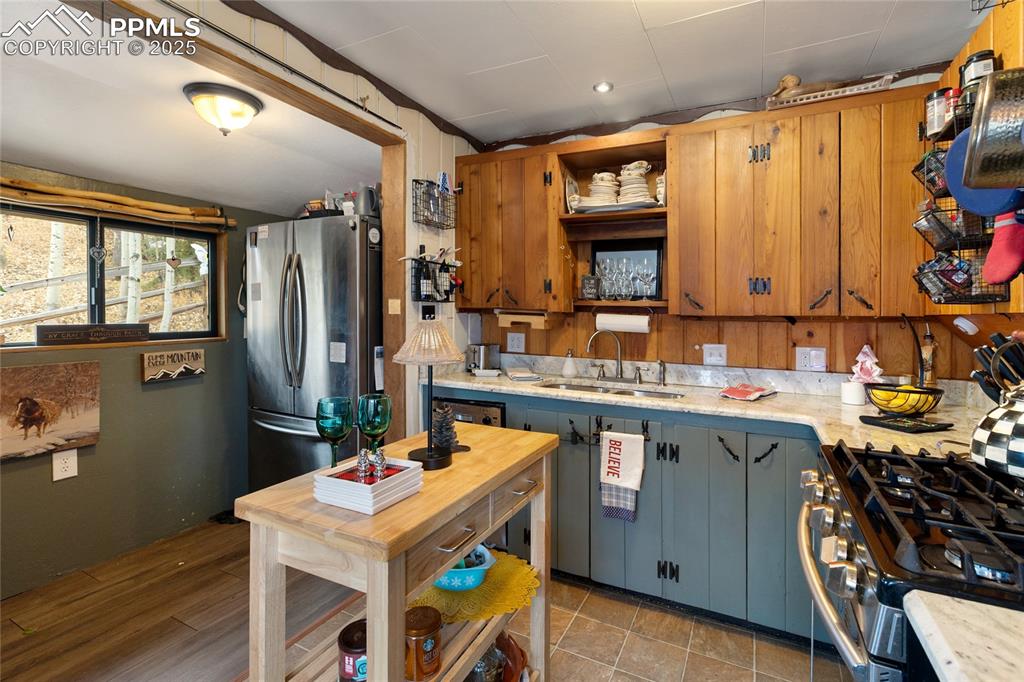 Kitchen featuring stainless steel appliances, rustic cupboards, and white stone counter tops