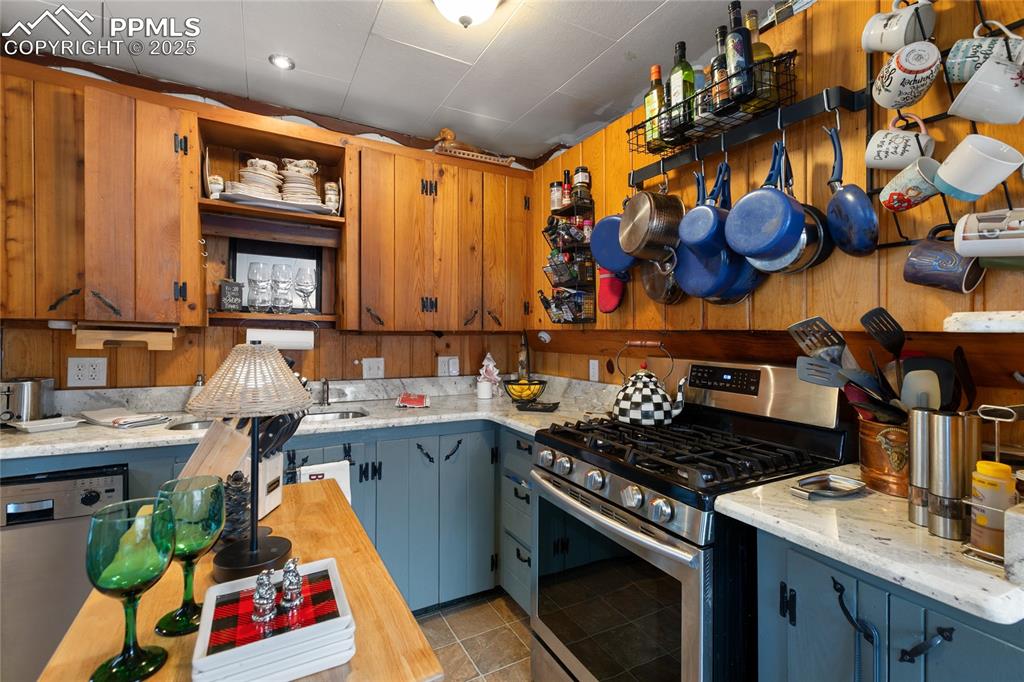 Kitchen featuring open shelves, stainless steel appliances, light tile patterned flooring, and light stone counters