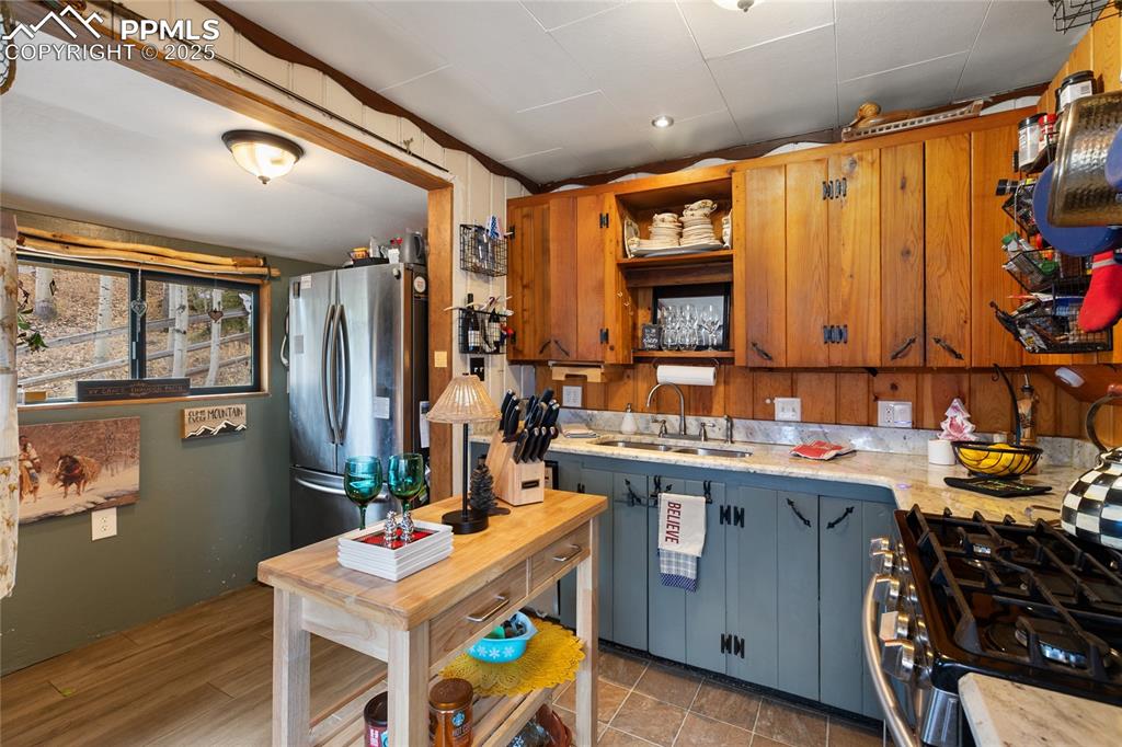 Kitchen featuring open shelves, gas range, freestanding refrigerator, vaulted ceiling, and light wood-type flooring