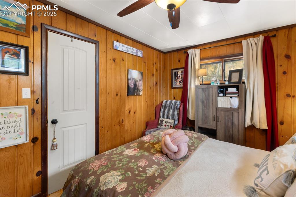 Main Bedroom with wood walls and a ceiling fan