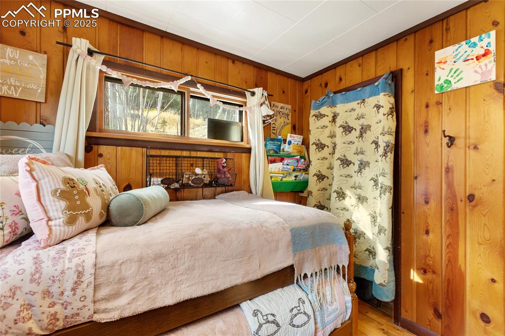 Bedroom with wooden walls and wood finished floors