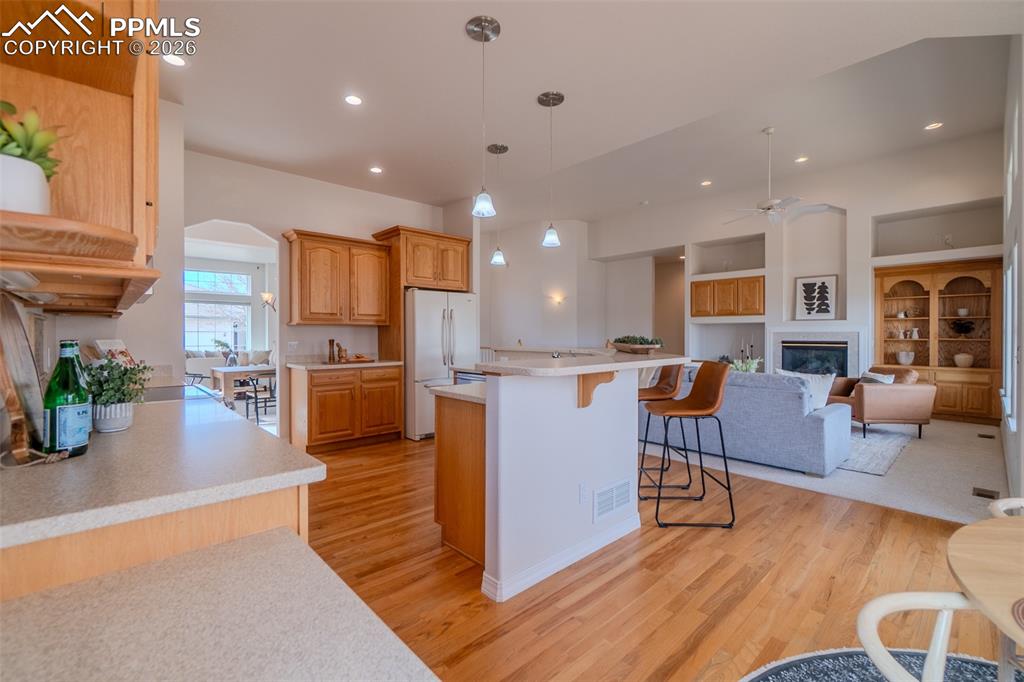 Kitchen featuring a kitchen bar, light countertops, decorative light fixtures, open floor plan