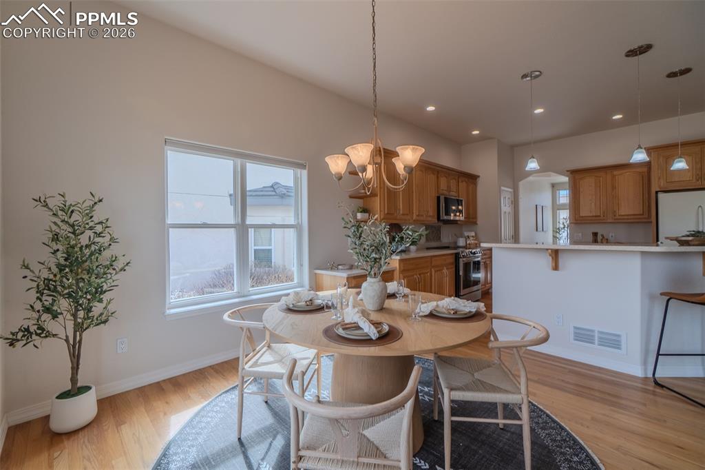 Dining area featuring light wood-style flooring, arched walkways, plenty of natural light, and hanging lights