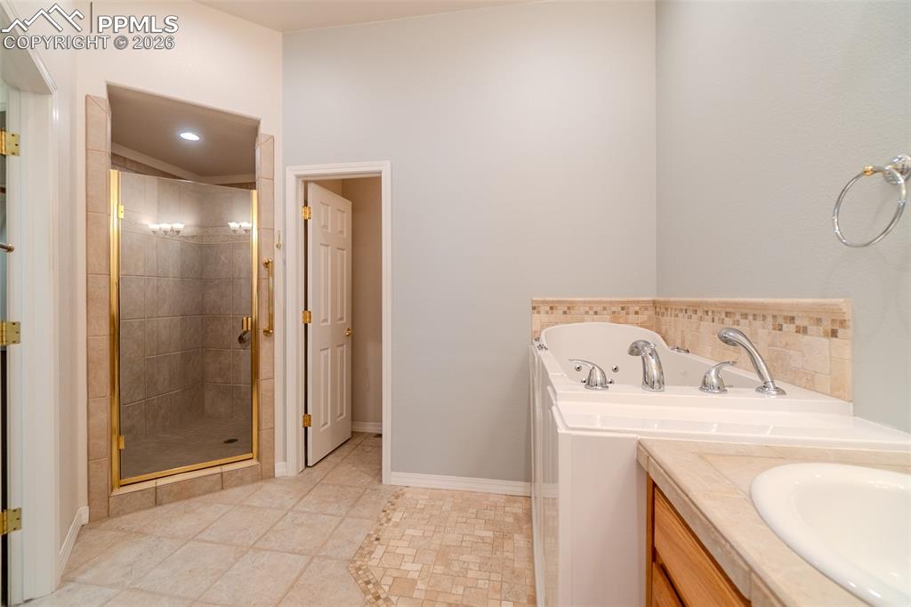 Full bath featuring vanity, a shower stall, a bath, and light tile patterned floors