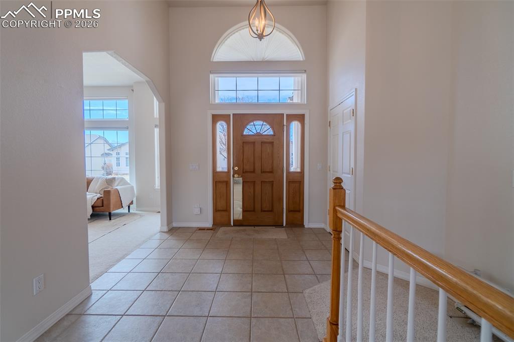 Foyer entrance featuring a high ceiling, light tile patterned floors, arched walkways, and plenty of natural light