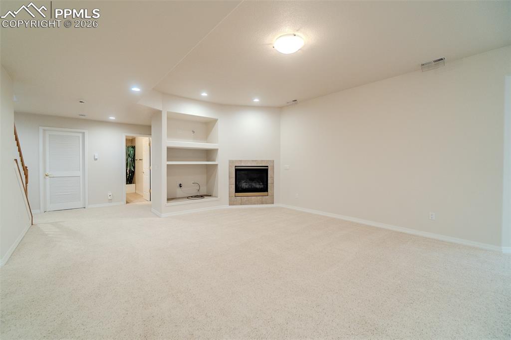 2nd living room with built in features, light carpet, a tiled fireplace, and recessed lighting