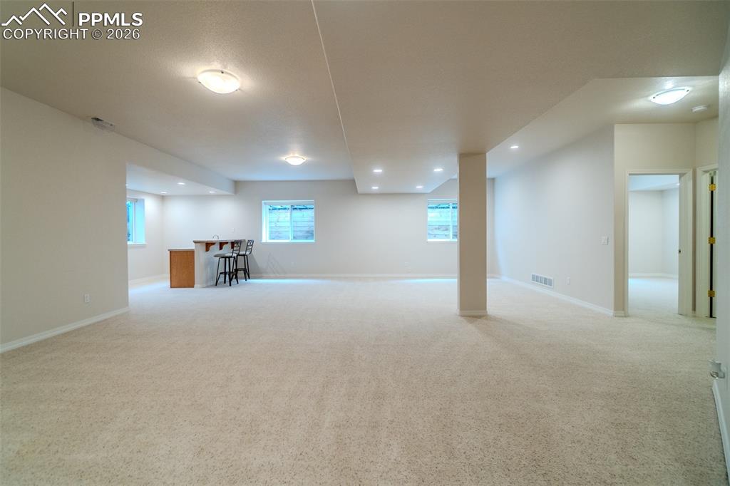 Basement with light carpet, recessed lighting, and bar