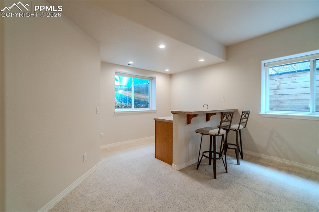 Indoor wet bar with light colored carpet, recessed lighting, and light countertops