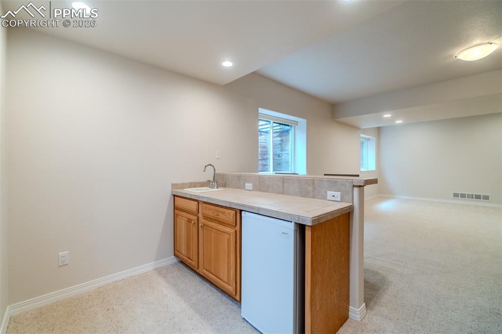 Kitchen featuring open floor plan, a peninsula, white dishwasher, light carpet, and recessed lighting