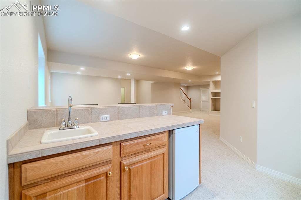 Kitchenette with a peninsula, light colored carpet, recessed lighting, and light wood finish cabinets