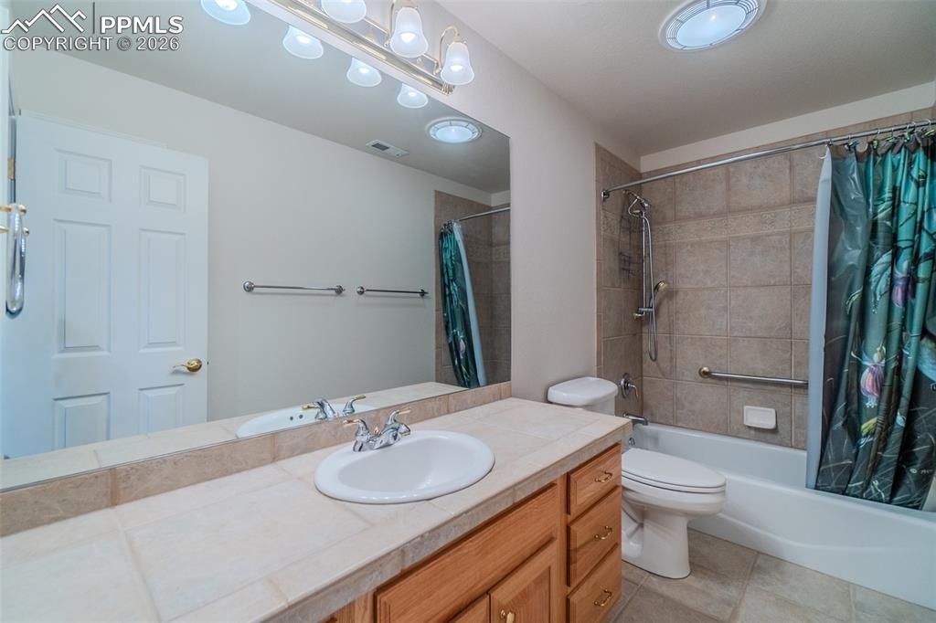 Full bath with vanity, shower / tub combo with curtain, and light tile patterned floors