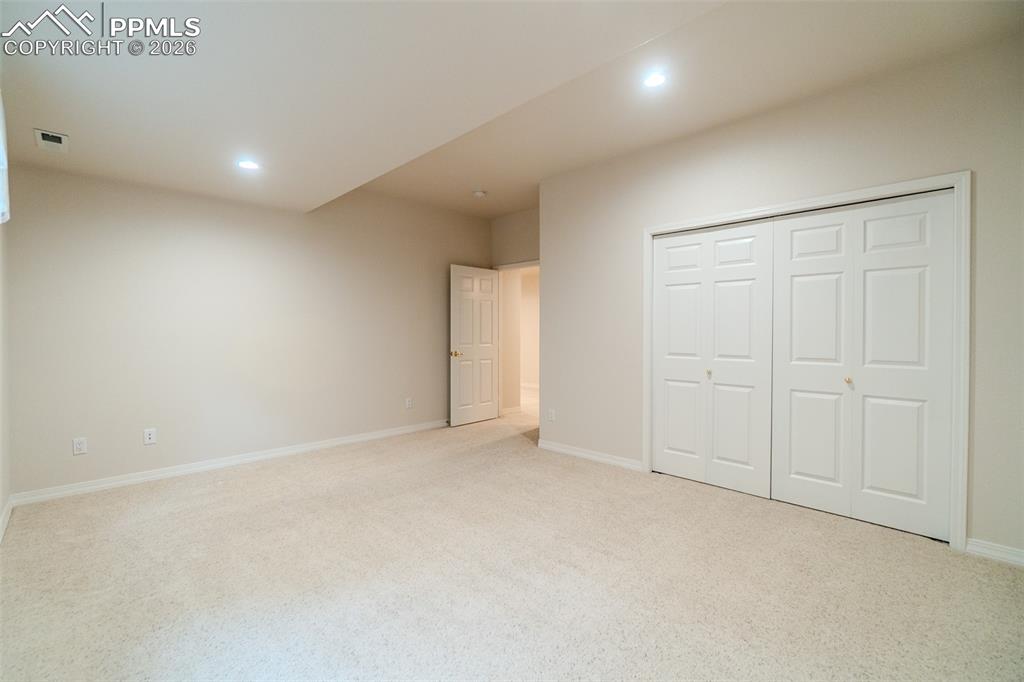 Bedroom featuring light colored carpet, recessed lighting, and a closet
