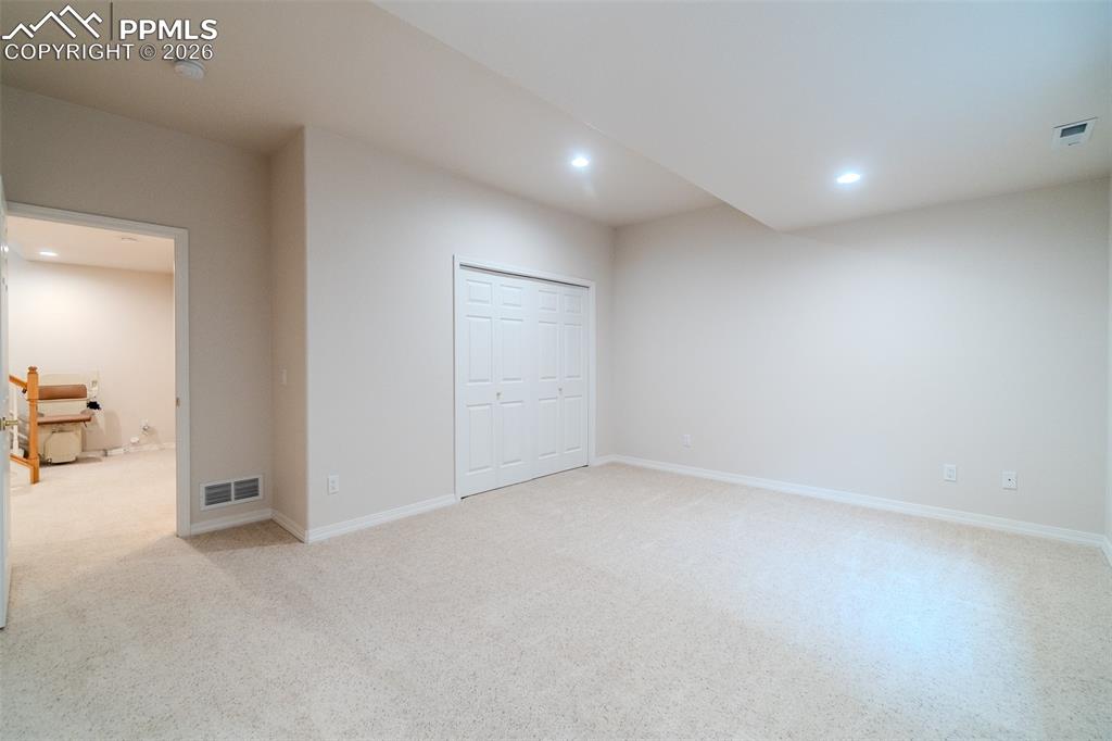 Bedroom in basement featuring light carpet, recessed lighting, and a closet