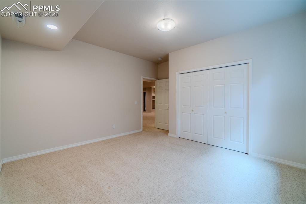 Bedroom in basement featuring light carpet and a closet