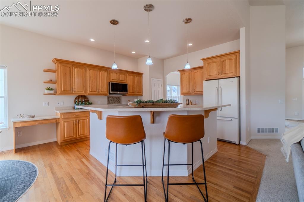 Kitchen with a kitchen bar, a kitchen island, freestanding refrigerator, and light countertops