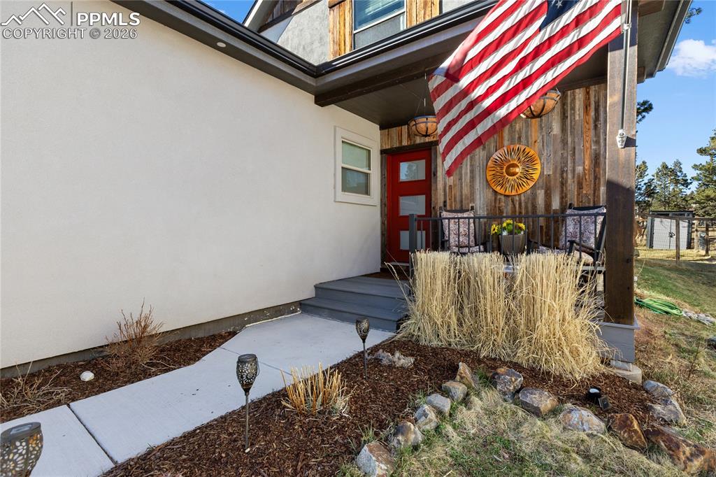 Property entrance with stucco siding and a wooden deck