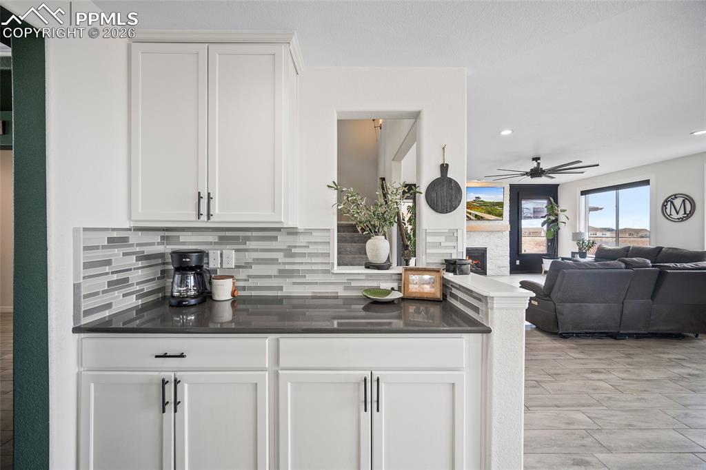 Bar featuring recessed lighting, ceiling fan, a warm lit fireplace, and decorative backsplash
