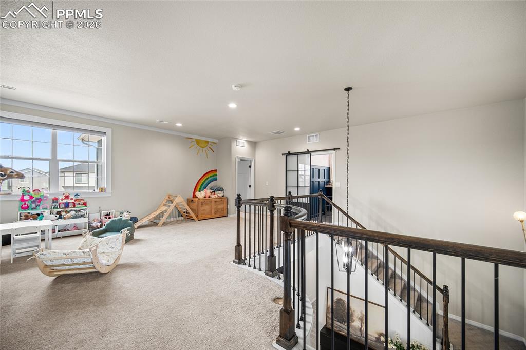 Rec room featuring carpet floors, a healthy amount of sunlight, a barn door, and recessed lighting