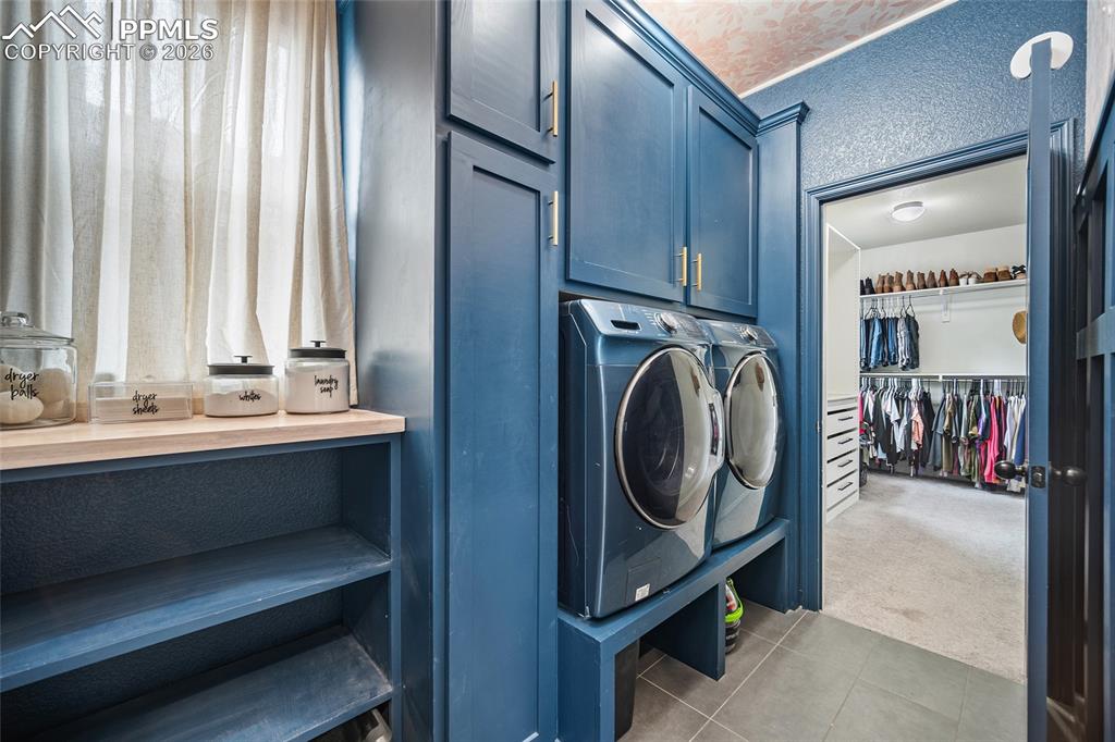 Laundry area featuring cabinet space, carpet floors, washer and clothes dryer, and tile patterned flooring