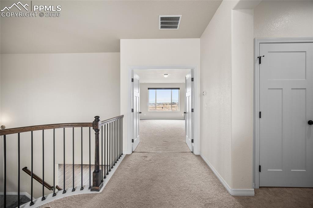 Hall featuring an upstairs landing, visible vents, baseboards, and carpet floors