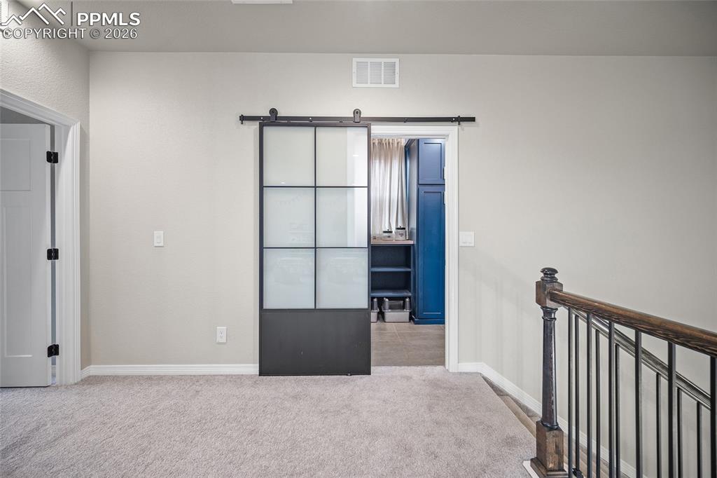 loft space with entry to laundry room that also connects to primary bed closet
