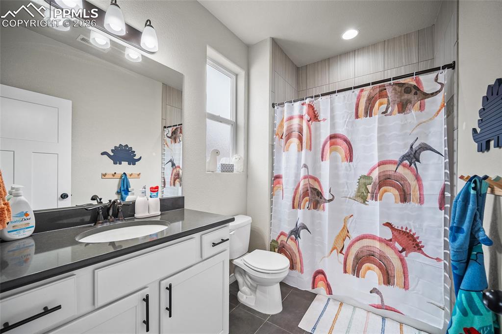 Bathroom featuring toilet, vanity, a shower with shower curtain, and tile patterned flooring