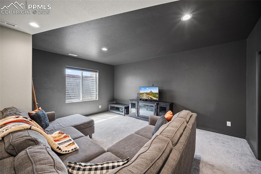 Carpeted living area featuring recessed lighting, visible vents, and baseboards