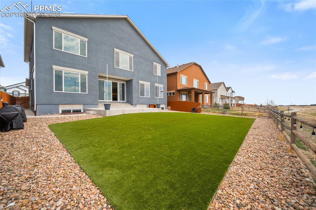 Rear view of house with a patio area, a fenced backyard, and turf lawn