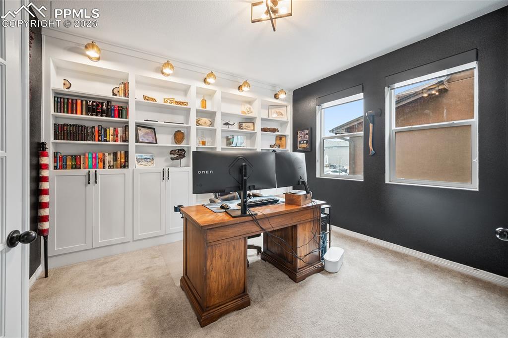 Office space featuring built in shelving and hard wired sconces.
