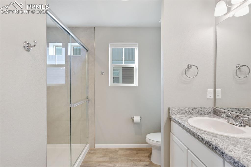 Full bath with vanity, a shower stall, and light wood-style flooring