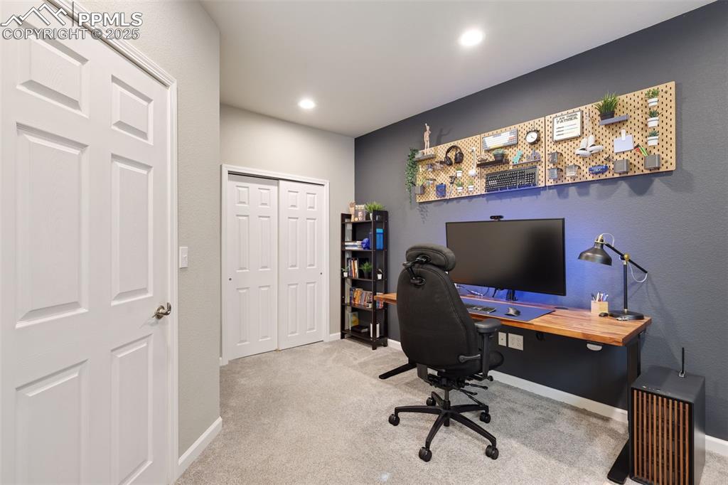 Home office with light colored carpet and recessed lighting