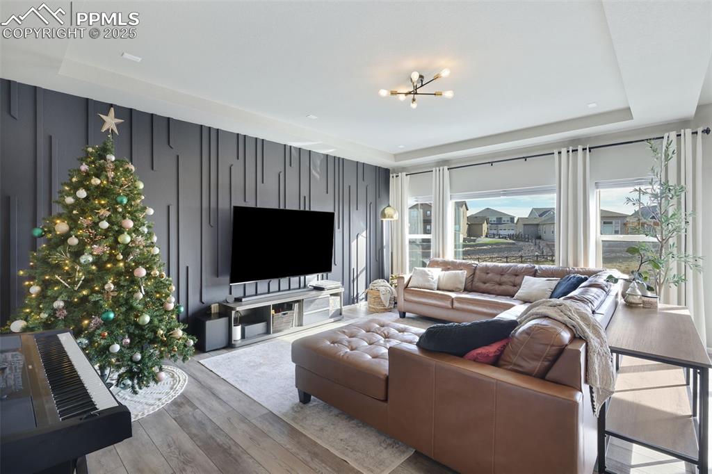 Living room featuring a raised ceiling, hardwood / wood-style flooring, and a chandelier