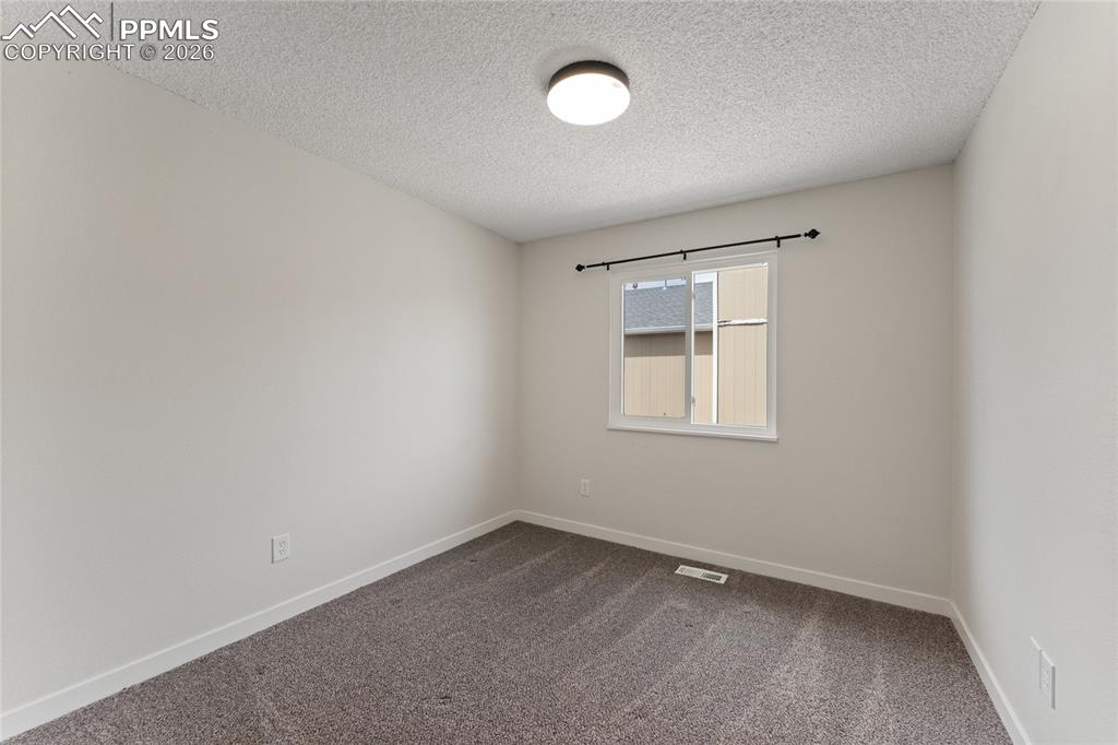 Unfurnished room featuring dark carpet and a textured ceiling