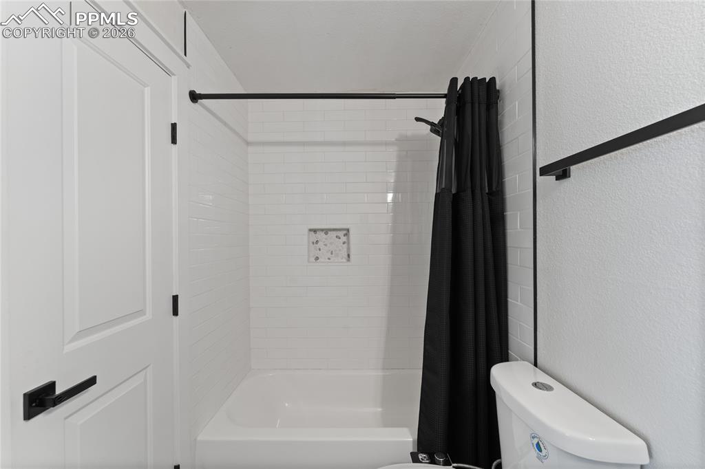 Full bath with a textured wall and shower / bath combo