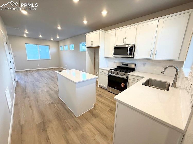 Kitchen with Quartz countertops, island, gas range, microwave, and dishwasher!