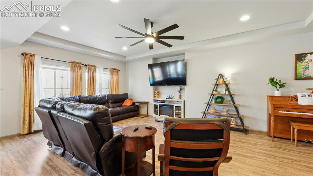 Spacious Living Room that features a lighted ceiling fan, luxury vinyl plank floors, an entertainment recess, and wall of windows with views of the backyard.