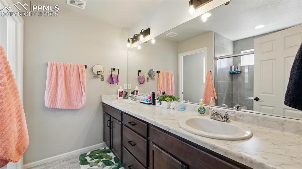 The Primary Bathroom has a dual sink vanity, mirror, and enclosed tiled shower.
