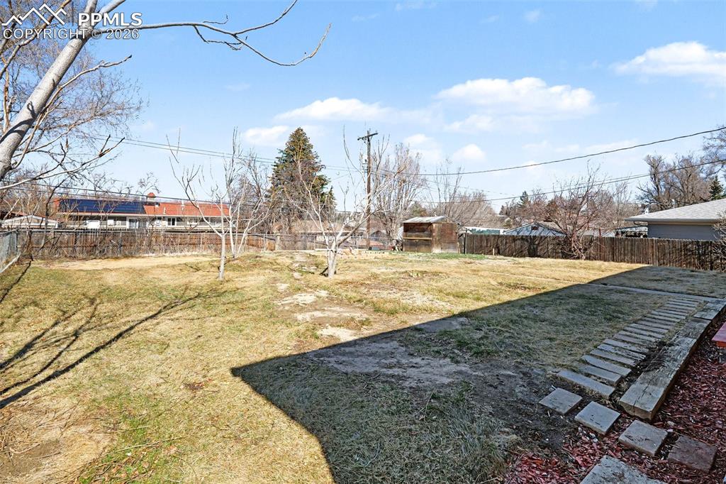 Fenced backyard offers mountain views, mature trees, and space to relax or play.