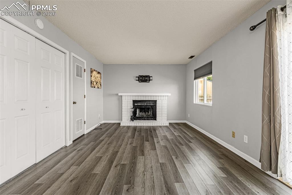 Unfurnished living room featuring a textured ceiling, dark wood-style flooring, and a fireplace