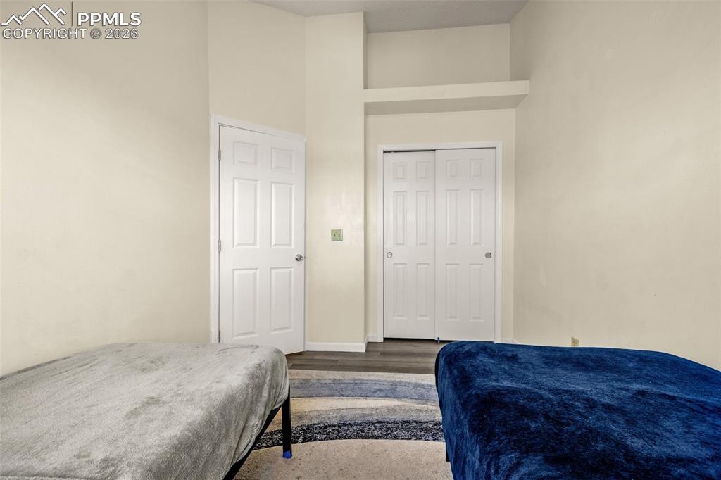 Bedroom with a closet, wood finished floors, and a towering ceiling