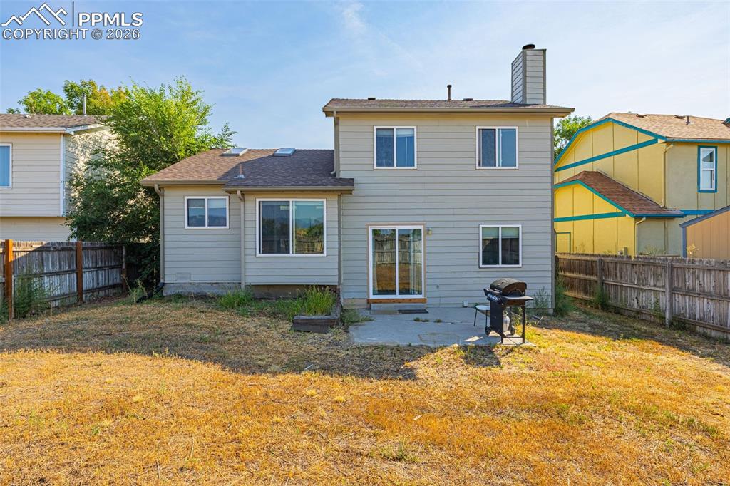 Back of house with a patio area, a fenced backyard, a chimney, and a shingled roof