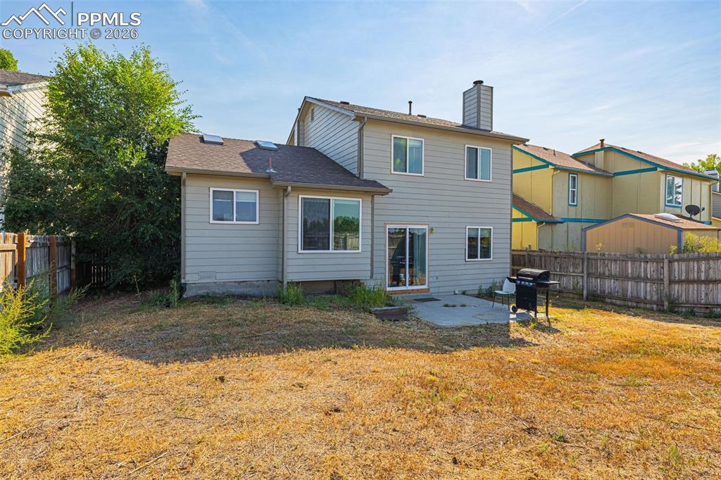 Back of house with a patio, a fenced backyard, a chimney, and a shingled roof