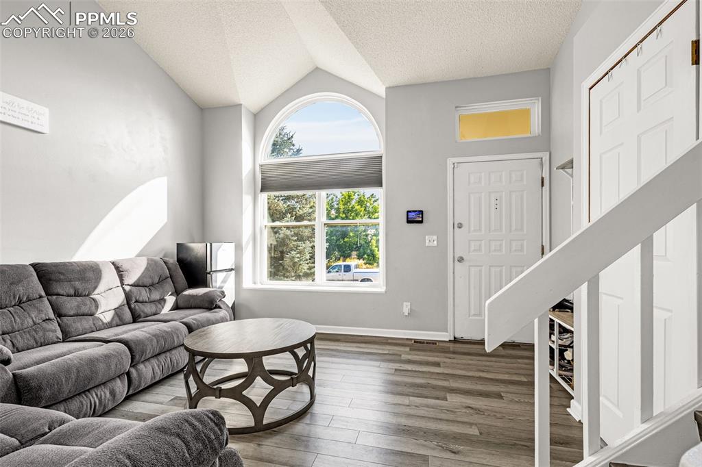Living area with a textured ceiling, wood finished floors, and lofted ceiling