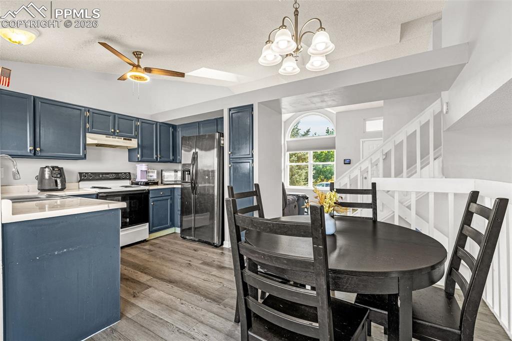Kitchen with light countertops, stainless steel fridge, white electric range oven, a textured ceiling, and light wood finished floors