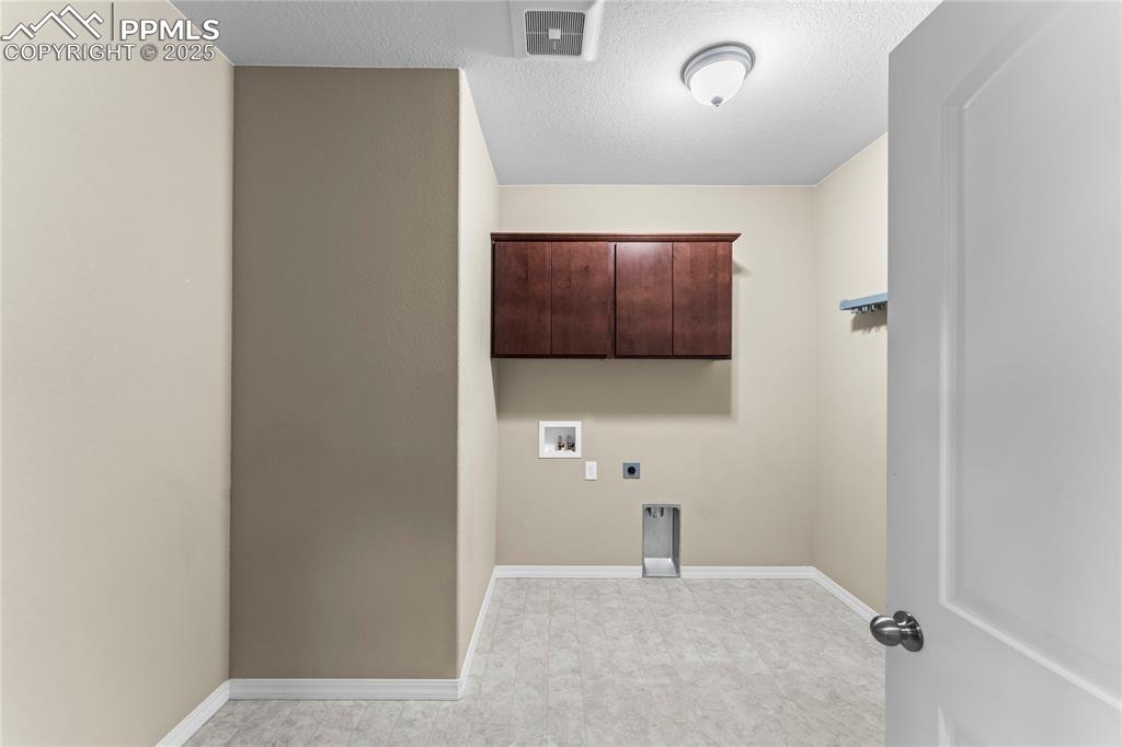 Laundry area featuring a textured ceiling, cabinet space, hookup for an electric dryer, and hookup for a washing machine